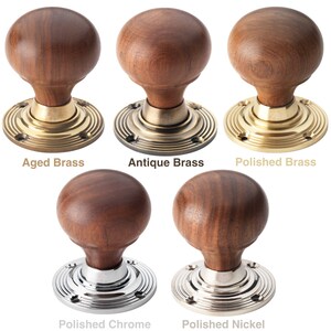 May include: A selection of wooden door knobs with different metal finishes. The knobs feature a round, dark wood design and are mounted on circular plates. Finishes include aged brass, antique brass, polished brass, polished chrome, and polished nickel.