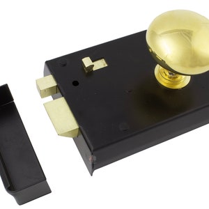 May include: A black mortise lock with a brass knob and brass-coloured bolt. The lock has a rectangular shape with a matching black strike plate. The knob is oval-shaped and shiny.