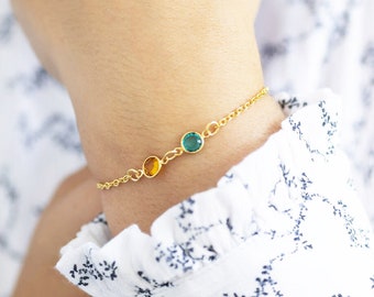 May include: A gold chain bracelet with three small gemstones. The gemstones are green, yellow, and green.