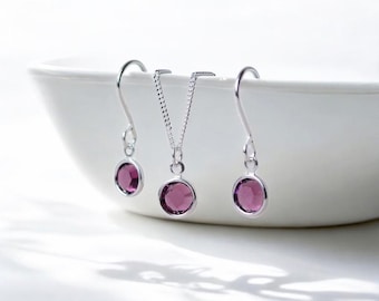 Könnte beinhalten: Ein Set aus silbernem Schmuck mit violetten Edelstein-Akzenten. Das Set enthält eine Halskette und ein Paar Ohrringe.
