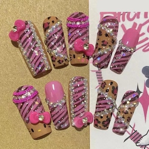 May include: Pink and brown striped false nails with rhinestones and Hello Kitty bows.