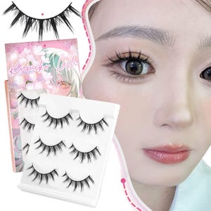 May include: A set of false eyelashes, with a pink and white box that reads "Kumiko Lash". The image shows several sets of black, wispy false eyelashes. The image also shows a close-up of a person's eye with applied false eyelashes.