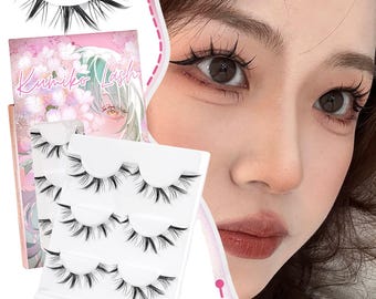 Könnte beinhalten: Ein Set schwarzer falscher Wimpern, zusammen mit einer rosa-weißen Schachtel mit der Aufschrift "Kumiko Lash". Das Bild zeigt auch eine Nahaufnahme eines Auges mit Eyeliner und Mascara.