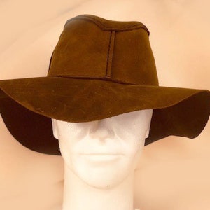 Puede incluir: Un sombrero marr&oacute;n de ala ancha con una textura similar al ante. El sombrero se lleva en una cabeza de maniqu&iacute;.
