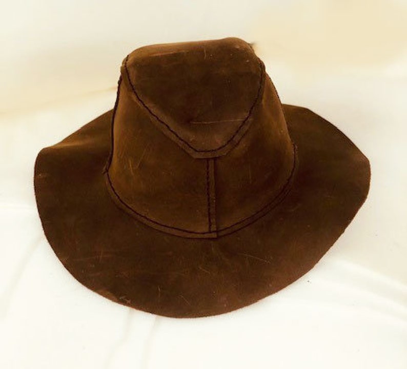 Puede incluir: Un sombrero de gamuza marr&oacute;n con un ala ancha y una corona puntiaguda.