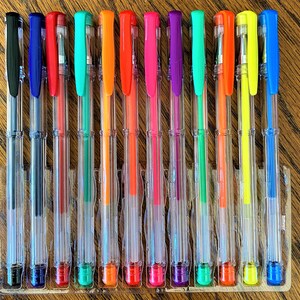 Pu&ograve; includere: Un set di 14 penne gel in un portapenne di plastica trasparente. Le penne sono disposte in fila e sono di diversi colori, tra cui nero, blu, rosso, verde, arancione, rosa, viola, giallo e verde neon. Le penne sono tutte trasparenti e hanno un cappuccio argentato.