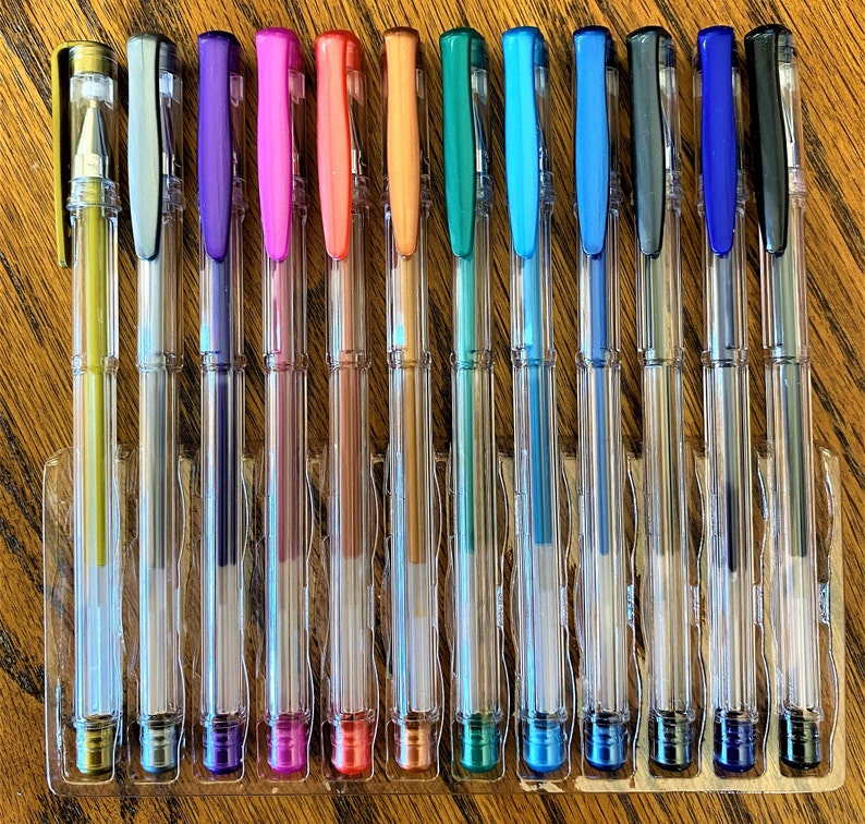 Pu&ograve; includere: Un set di 14 penne in plastica trasparente con inchiostro metallizzato. Le penne sono disposte in fila e presentano una variet&agrave; di colori, tra cui oro, argento, viola, rosa, rosso, arancione, verde, blu e nero.
