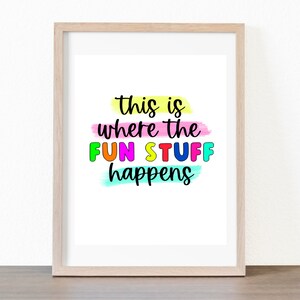 May include: A framed print with the text "This is where the FUN STUFF happens" in colorful letters on a white background. The text is surrounded by colorful brushstrokes.