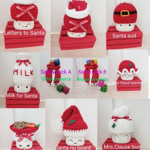 Op de afbeelding: Negen verschillende gehaakte bekertoppers, elk met een ander kerstthema. De toppers zijn gemaakt van wit en rood garen en hebben verschillende ontwerpen, waaronder kerstmanmutsen, melkpakken en koekjes. De toppers worden gepresenteerd op rode houten kisten.