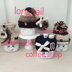 May include: Four white ceramic mugs with different knitted hats. The mugs have a smiling face and are decorated with coffee-themed details. The hats are brown, black, and beige with pom-poms. The text "coffee sack" and "coffee shop" are written on the image.