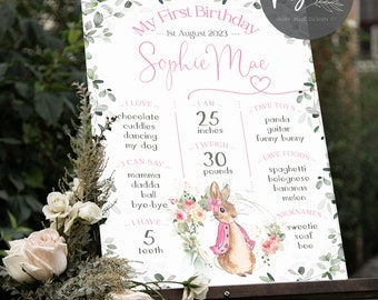 May include: A pink and green first birthday sign with a bunny illustration. The sign lists the child's age, weight, height, favorite foods, toys, and things they can say. The sign reads "My First Birthday... 1st August 2023... Sophie Mae"