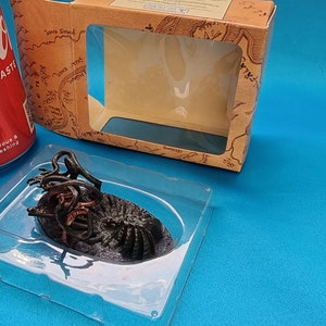 May include: A black and brown plastic model of a creature with multiple tentacles, sitting in a clear plastic tray. The model is in a cardboard box with a clear window.