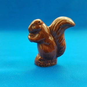 May include: A brown ceramic squirrel figurine with a bushy tail. The figurine is standing on its hind legs and has its front paws raised to its chest. The figurine is made in England.