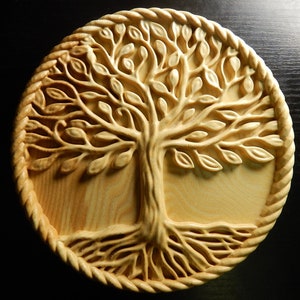 Op de afbeelding: Een ronde houten wanddecoratie met een gesneden boom des levens ontwerp. De boom heeft ingewikkelde takken en bladeren, en de wortels zijn ook gedetailleerd gesneden. Het hout is lichtbruin van kleur.