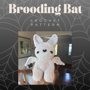 Könnte beinhalten: Gehäkelter Fledermaus-Plüsch in Hellgrau, mit schwarzen herzförmigen Augen. Das Bild enthält den Text "Floppy Friends Brooding Bat Crochet Pattern" und den Instagram-Handle @sweetcremesco.