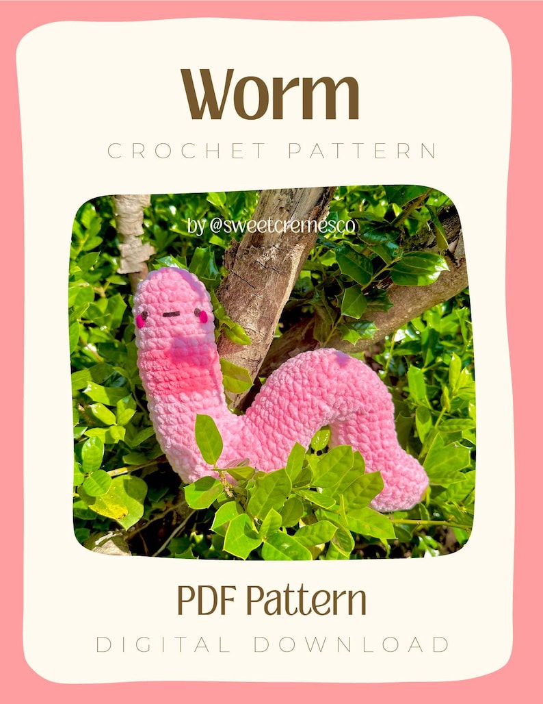 May include: A pink crocheted worm amigurumi toy with a pink and white face, sitting on a branch of a green bush. The image includes the text "Worm Crochet Pattern by @sweetcremesco PDF Pattern Digital Download".