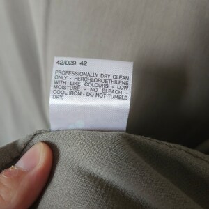 Op de afbeelding: Een wit waslabel met de tekst "Professionally dry clean only - Perchloroethylene with like colours - Low moisture - No bleach - Cool iron - Do not tumble dry" en de nummers "42/029 42".