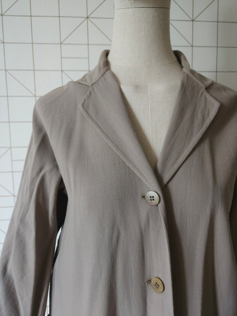 Op de afbeelding: Een lange, lichtbruine blazer met een reverskraag en drie knopen. De blazer is gemaakt van een zachte, gestructureerde stof.