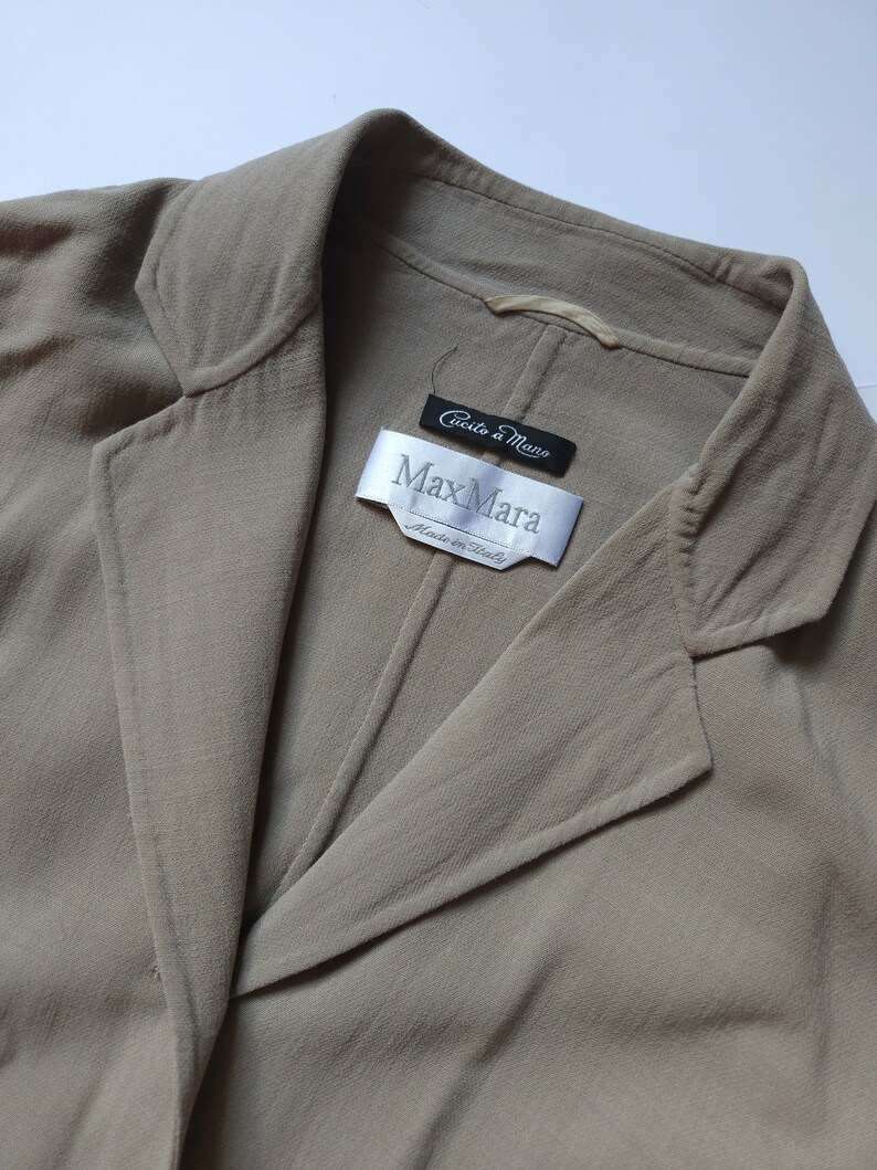 Op de afbeelding: Een beige blazer met een Max Mara-label met de tekst "Ciuccio a Mano" en "Made in Italy".