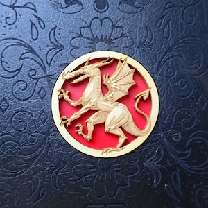 May include: A wooden dragon cutout with a red background, mounted on a black leather surface.