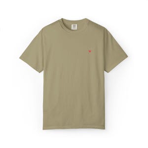 May include: An olive-green t-shirt with short sleeves and a small red triangle emblem on the chest. The t-shirt has a crew neck and a loose fit. The material looks soft and comfortable.