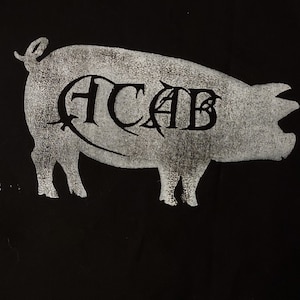 K&ouml;nnte beinhalten: Eine wei&szlig;e Silhouette eines Schweins mit den Buchstaben "ACAB" innerhalb der Silhouette auf schwarzem Hintergrund.