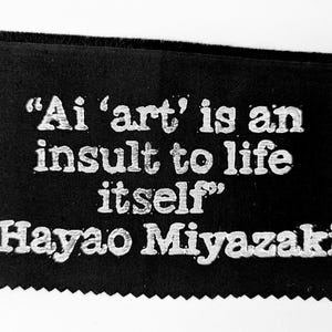 K&ouml;nnte beinhalten: Schwarzwei&szlig;bild eines Zitates von Hayao Miyazaki auf schwarzem Stoffhintergrund. Das Zitat lautet: "Ai 'art' is an insult to life itself".