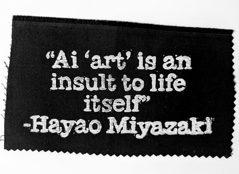 K&ouml;nnte beinhalten: Schwarzwei&szlig;bild eines Zitates von Hayao Miyazaki auf schwarzem Stoffhintergrund. Das Zitat lautet: "Ai 'art' is an insult to life itself".
