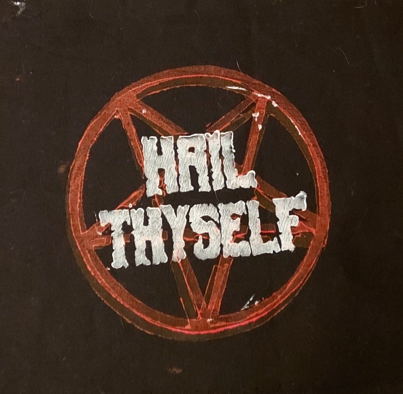 K&ouml;nnte beinhalten: Ein schwarzer Patch mit einem roten Pentagramm und den Worten "Hail Thyself" in wei&szlig;en Buchstaben.
