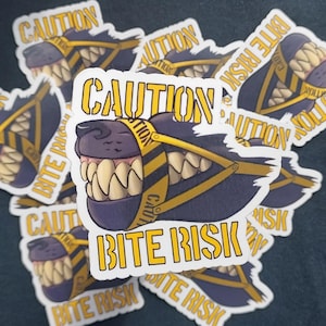Puede incluir: Un conjunto de pegatinas con un perro de dibujos animados con dientes afilados y una cinta de precaución amarilla alrededor de su boca. Las pegatinas dicen "Precaución Riesgo de Mordida" en letras amarillas sobre un fondo blanco.