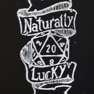 K&ouml;nnte beinhalten: Eine Schwarzwei&szlig;illustration eines zwanzigseitigen W&uuml;rfels mit den Worten "Naturally Lucky" auf einem Banner dar&uuml;ber.