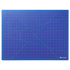 May include: A blue self-healing cutting mat with a grid pattern and diagonal lines. The mat has inch measurements along the edges and a "The Art Institutes" logo in the bottom right corner.