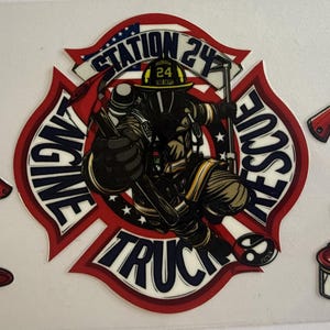 Könnte beinhalten: Ein Aufkleberbogen mit einem zentralen kreisförmigen Emblem, das einen Feuerwehrmann, den Text STATION 24 ENGINE TRUCK und eine US-Flagge zeigt. Um das Emblem herum sind vier rotstielige Äxte und zwei rote Feuerwehrhelme mit Goldvisier.