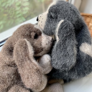 May include: Two plush toy dogs, one brown and one gray, are cuddling together. The brown dog is on the left and the gray dog is on the right. The dogs are both made of soft, fluffy material and have realistic features.