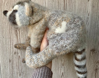 Gestrickter großer realistischer Waschbär mit einem Muster aus Herz auf der Rückseite und einer Blume auf dem Bauch Gehäkelter realistischer Waschbär Waschbär Stofftier