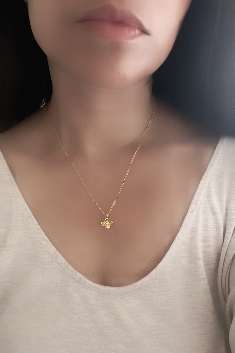 May include: A gold chain necklace with a small bee pendant.