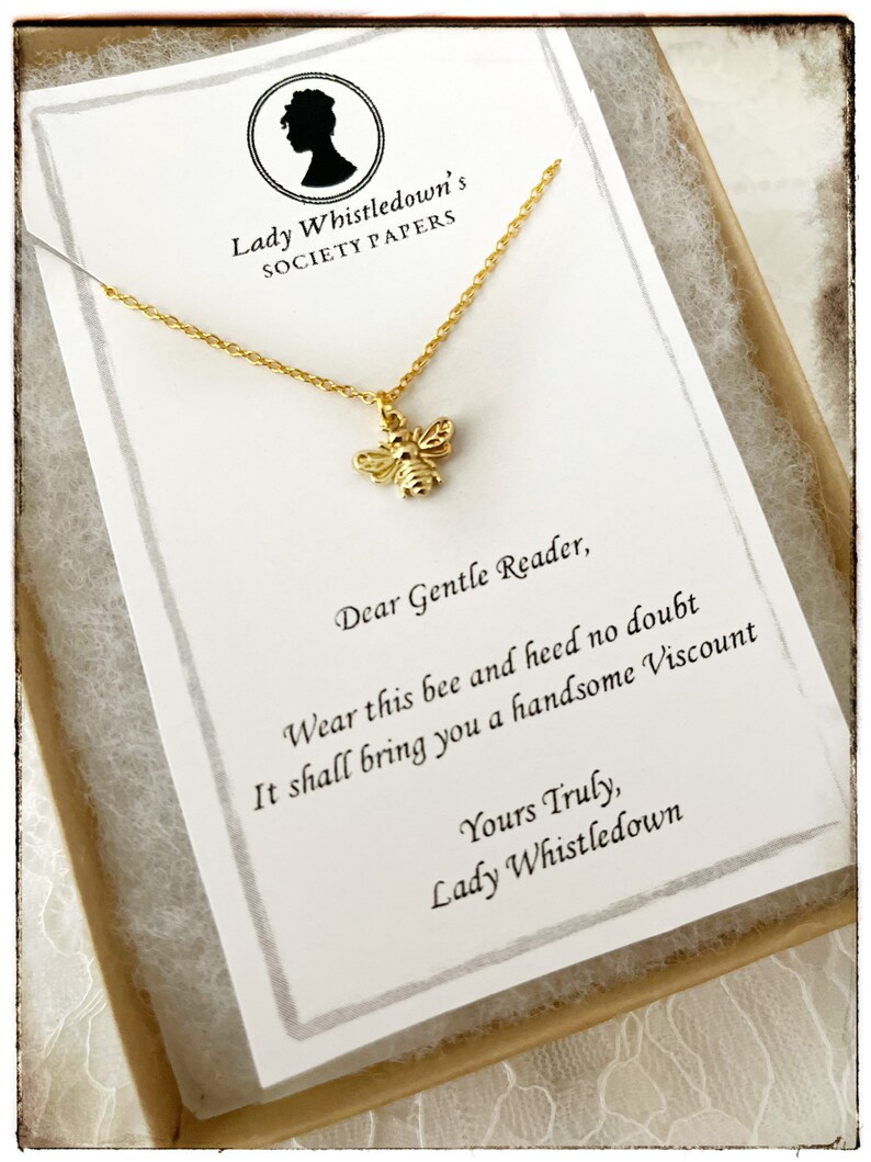 May include: A gold bee charm necklace in a small box with a note that reads "Lady Whistledown's Society Papers. Dear Gentle Reader, Wear this bee and heed no doubt It shall bring you a handsome Viscount Yours Truly, Lady Whistledown"