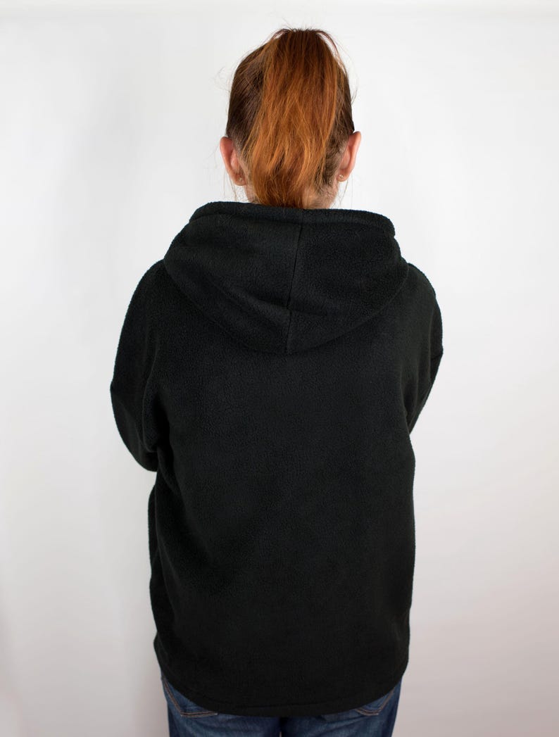May include: A black fleece hoodie with a hood. The hoodie is pulled up and the hood is covering the person's head.