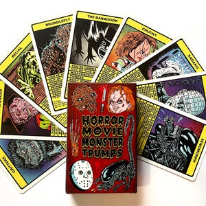 May include: A deck of Horror Movie Monster Trumps cards featuring illustrations of iconic horror movie monsters such as Freddy Krueger, Chucky, and the Xenomorph. The cards are fanned out around a red box with the game's title.