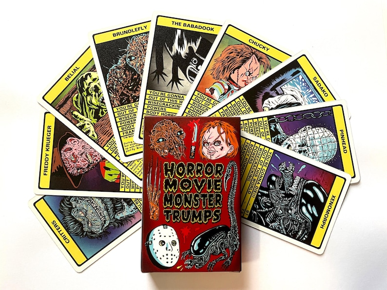 May include: A deck of Horror Movie Monster Trumps cards featuring illustrations of iconic horror movie monsters such as Freddy Krueger, Chucky, and the Xenomorph. The cards are fanned out around a red box with the game's title.