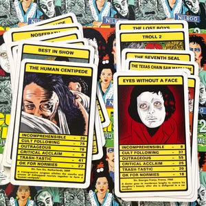 May include: A set of 10 playing cards featuring cult film movie posters. The cards are white with black text and feature titles such as "The Human Centipede", "Eyes Without a Face", "The Lost Boys", and "Troll 2".