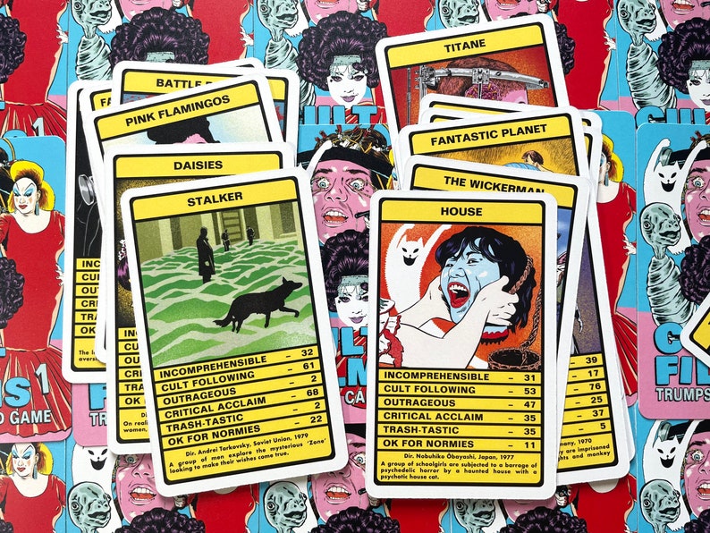 May include: A set of colourful playing cards with a horror movie theme. The cards feature titles such as "The Wickerman", "House", "Fantastic Planet", and "Pink Flamingos". Each card has a rating system for "Incomprehensible", "Cult Following", "Outrageous", "Critical Acclaim", "Trash-Tastic", and "OK for Normies".