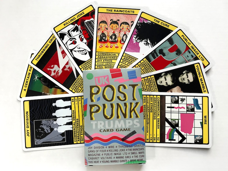 以下が含まれることがあります： カラフルなデザインの「UK Post Punk Trumps」というトランプ。カードには、ジョイ・ディヴィジョン、ワイヤー、スロビング・グリズリー、キリング・ジョーク、ザ・レインコート、ザ・キュアー、パブリック・イメージ・リミテッド、ヤング・マーブル・ジャイアンツなど、さまざまなイギリスのポストパンクバンドの画像が描かれています。