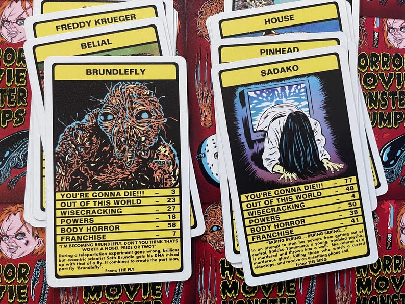 May include: A set of yellow and black playing cards featuring illustrations of horror movie characters. The cards include characters like Freddy Krueger, Belial, Brundlefly, Pinhead, Sadako, and House. Each card has a character name, a "You're Gonna Die!!!" section with stats, and a "Franchise" section with a quote and the movie title.