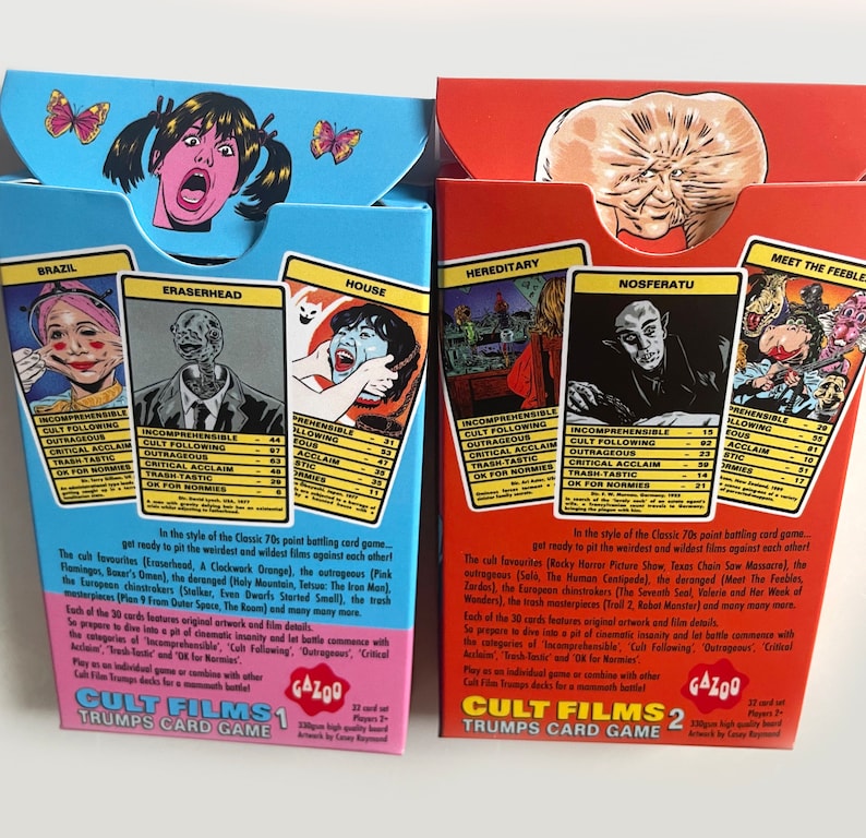 May include: Two boxes of Cult Films Trump Card Games. The boxes are blue and red and feature illustrations of characters from the films. The boxes are labelled Cult Films 1 and Cult Films 2. The back of the boxes list the categories of the game: Incomprehensible, Cult Following, Outrageous, Critical Acclaim, Trash-Tastic, and OK for Normies.