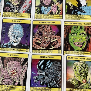May include: A set of trading cards featuring illustrations of horror movie characters. Each card has a yellow background with black text and a colourful illustration of a character. The text on the cards includes the character's name, the movie they are from, and statistics about their powers and abilities. The characters include Leatherface, Leprechaun, Michael Myers, Pinhead, Pumpkinhead, Regan McNeil, The Thing, Xenomorph, and Zaat.