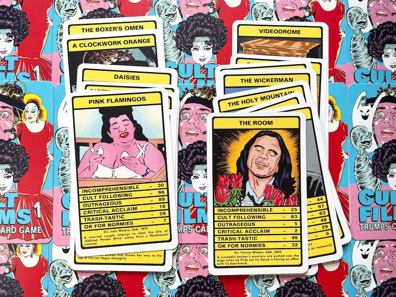 May include: A set of colourful playing cards featuring illustrations of cult film characters. The cards include titles such as "The Room", "Pink Flamingos", and "The Holy Mountain". Each card has a rating system for "Incomprehensible", "Cult Following", "Outrageous", "Critical Acclaim", "Trash-Tastic", and "OK for Normies".