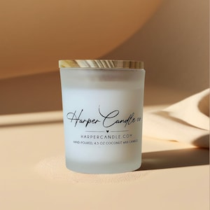 Może przedstawiać: Świeca z matowego szkła z drewnianą pokrywką. Świeca ma białe wnętrze z wosku i zawiera napis "Harper Candle co." czarną czcionką. Etykieta zawiera r&oacute;wnież napis "Hand-poured, 127.5 g coconut wax candles."