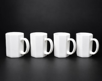 May include: Four white, geometric-shaped mugs with curved handles are arranged in a row against a black background. The mugs have a modern, minimalist design, suitable for coffee, tea, or other beverages.