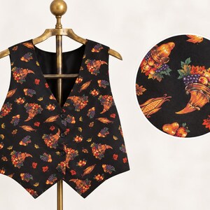 May include: A black vest featuring a repeating pattern of cornucopias filled with autumn fruits, vegetables, and leaves. The vest has a V-neckline, a button-front closure, and a pointed hemline. A circular inset shows a detailed view of the print.